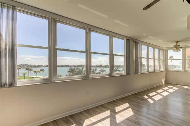 unfurnished sunroom with a water view and ceiling fan