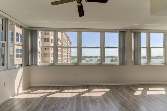 unfurnished sunroom with a water view and ceiling fan