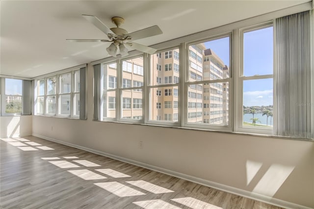 unfurnished sunroom with ceiling fan and a water view