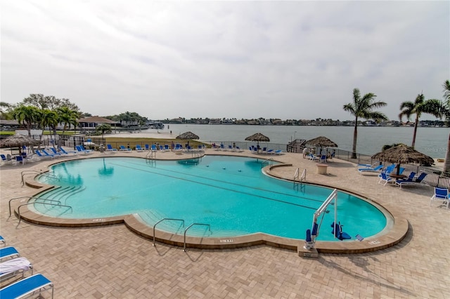 community pool featuring a water view, fence, and a patio