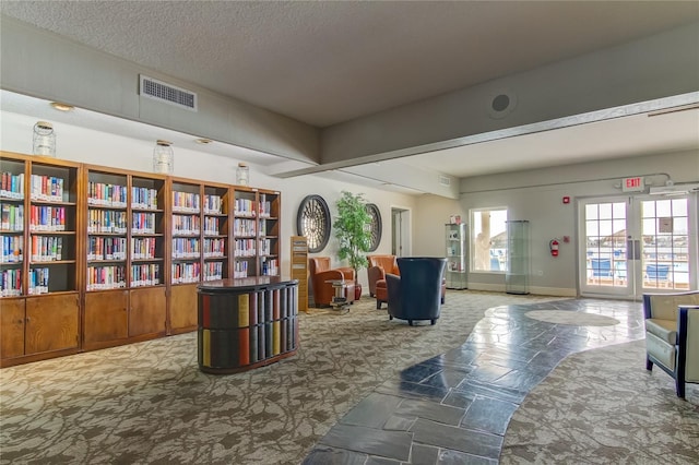 sitting room featuring carpet, french doors, visible vents, a textured ceiling, and baseboards