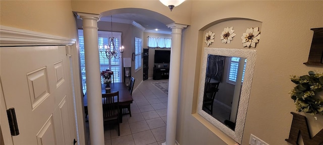 corridor featuring decorative columns, a notable chandelier, light tile floors, a wealth of natural light, and crown molding