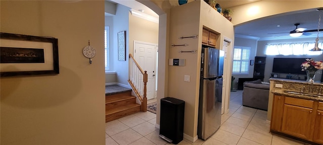 kitchen with crown molding, stainless steel refrigerator, ceiling fan, and dark stone countertops