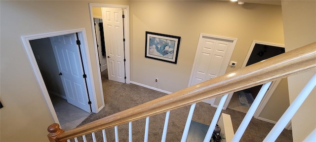 staircase featuring dark colored carpet