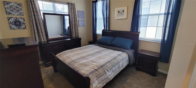 bedroom with dark carpet and multiple windows