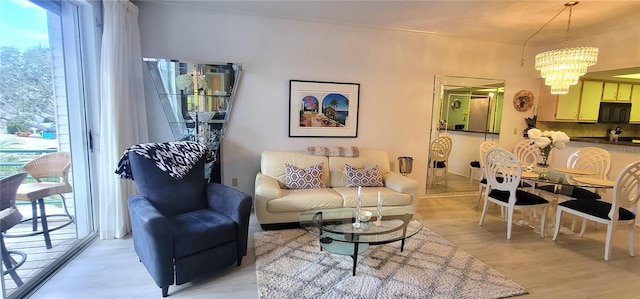 living room with a wealth of natural light, light hardwood / wood-style floors, and an inviting chandelier