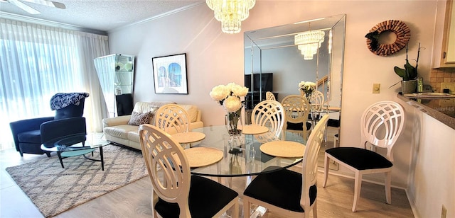 dining area featuring light hardwood / wood-style floors, ornamental molding, a textured ceiling, and an inviting chandelier