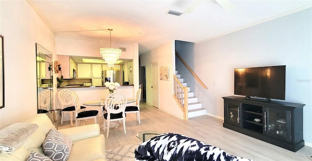 living room with ceiling fan with notable chandelier, a textured ceiling, light hardwood / wood-style floors, and ornamental molding