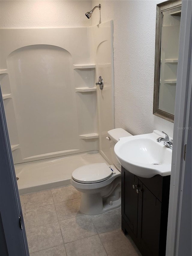 bathroom featuring a shower, toilet, vanity, and tile flooring