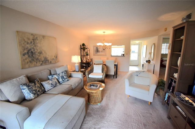 carpeted living room featuring an inviting chandelier and a textured ceiling