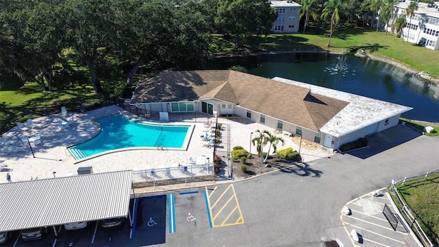 view of swimming pool with a patio area, a lawn, and a water view