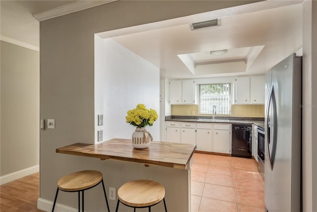 kitchen featuring stainless steel refrigerator, white cabinetry, sink, a kitchen bar, and black dishwasher