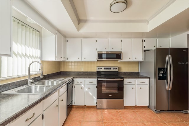 kitchen featuring stainless steel appliances, white cabinetry, light tile patterned floors, sink, and a tray ceiling