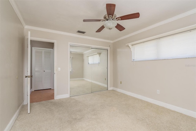 unfurnished bedroom featuring ornamental molding, multiple windows, light colored carpet, and ceiling fan