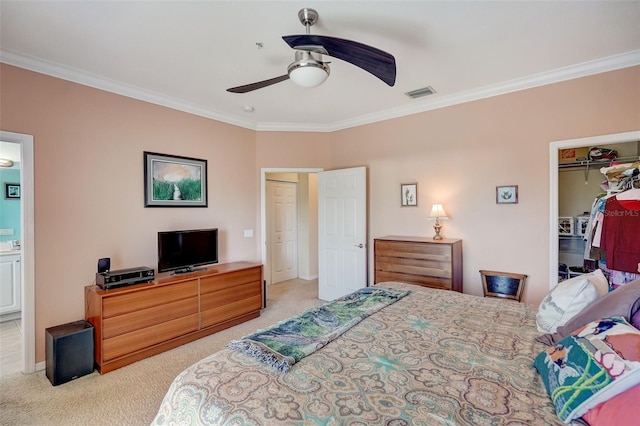 carpeted bedroom featuring ceiling fan, ornamental molding, a closet, and a walk in closet