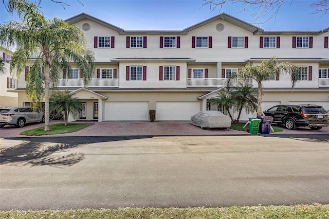 multi unit property with a garage, driveway, and stucco siding