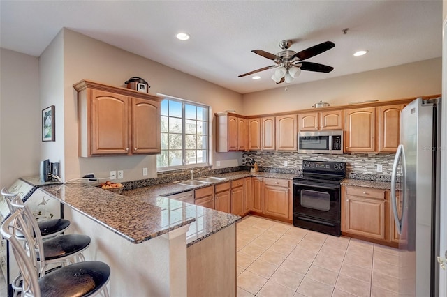 kitchen with a kitchen breakfast bar, light tile patterned floors, appliances with stainless steel finishes, ceiling fan, and kitchen peninsula