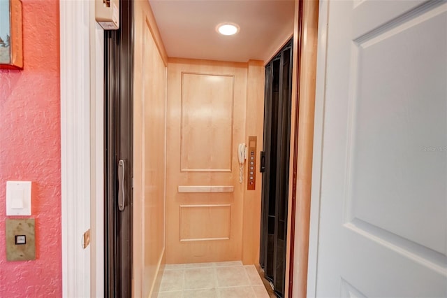 hallway with elevator and light tile patterned floors