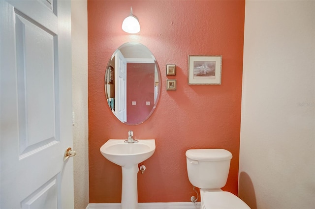 bathroom with a textured wall and toilet