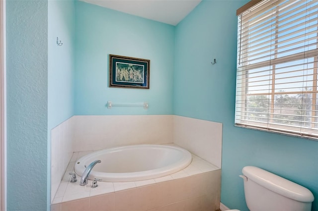 bathroom featuring a relaxing tiled tub and toilet