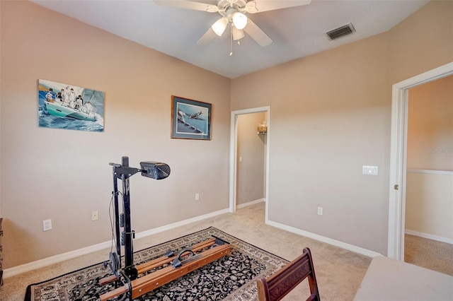 exercise room with ceiling fan and light carpet