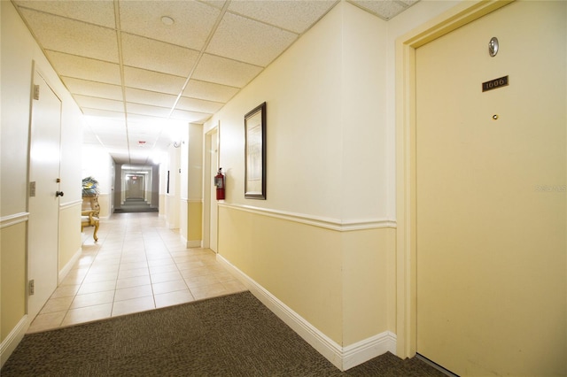 hallway with light tile floors and a drop ceiling