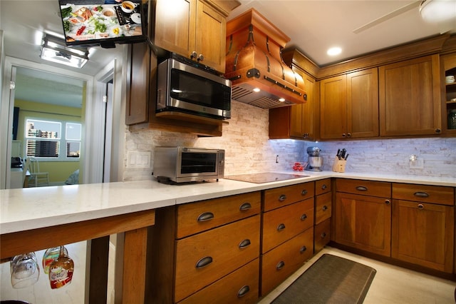 kitchen with backsplash, black electric cooktop, premium range hood, and light stone countertops