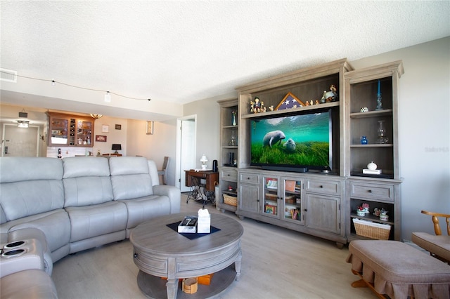 living room featuring a textured ceiling, rail lighting, and light hardwood / wood-style floors