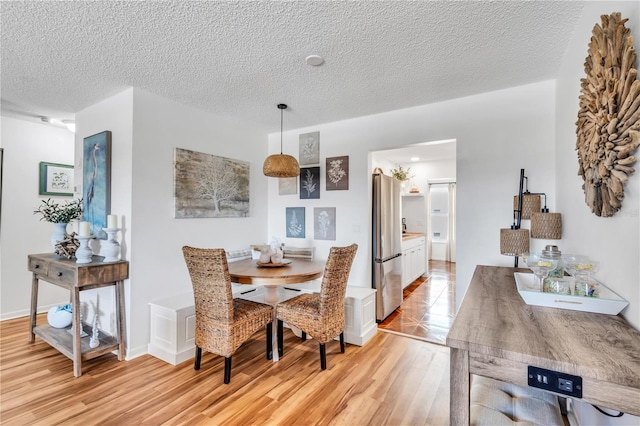 dining space featuring light hardwood / wood-style flooring and a textured ceiling