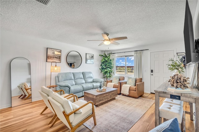 living room with ceiling fan, light hardwood / wood-style flooring, and a textured ceiling