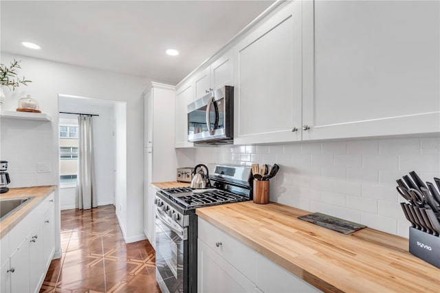 kitchen with backsplash, wooden counters, tile patterned floors, appliances with stainless steel finishes, and white cabinetry