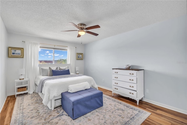 bedroom featuring hardwood / wood-style floors, ceiling fan, and a textured ceiling