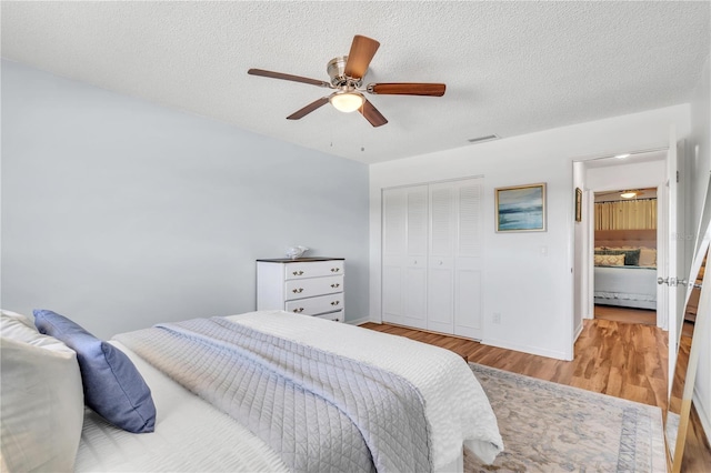 bedroom with a textured ceiling, a closet, ceiling fan, and light hardwood / wood-style floors