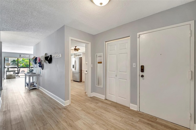 entrance foyer featuring ceiling fan, light hardwood / wood-style flooring, and a textured ceiling