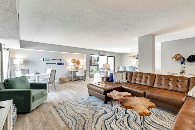 living room featuring light hardwood / wood-style flooring, a textured ceiling, and an inviting chandelier