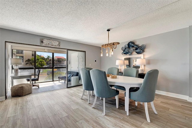 dining area featuring an inviting chandelier, a textured ceiling, and light hardwood / wood-style flooring