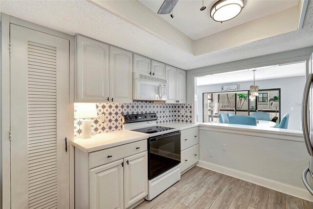 kitchen with light hardwood / wood-style floors, ceiling fan, white appliances, white cabinets, and backsplash