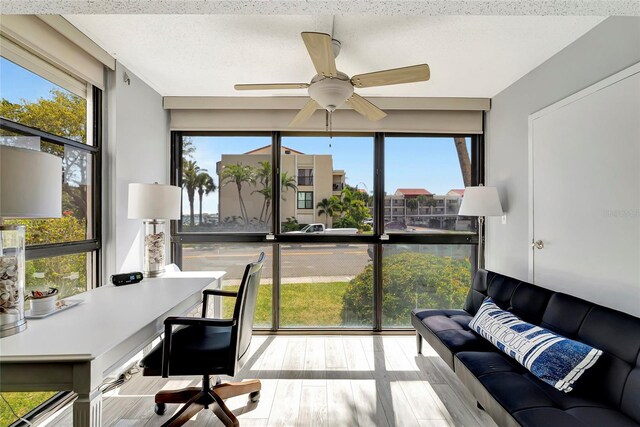 home office featuring a textured ceiling, ceiling fan, a wealth of natural light, and light hardwood / wood-style flooring