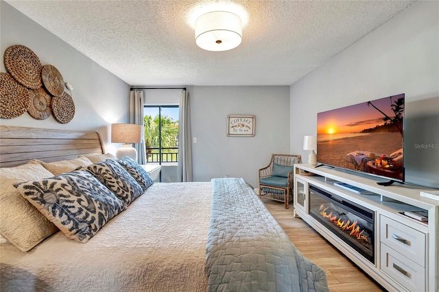 bedroom featuring a textured ceiling, access to outside, and light wood-type flooring