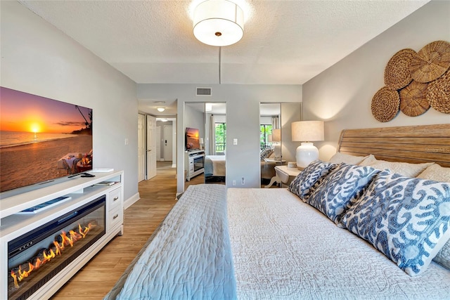 bedroom with a closet, light hardwood / wood-style flooring, and a textured ceiling