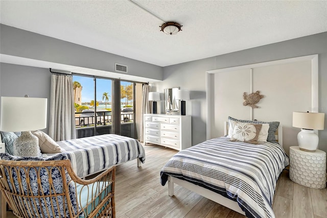 bedroom with a textured ceiling, access to outside, and light wood-type flooring