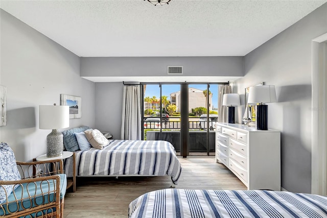 bedroom featuring light hardwood / wood-style floors, access to outside, and a textured ceiling