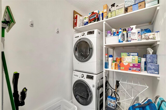 washroom featuring stacked washer / drying machine and a textured ceiling