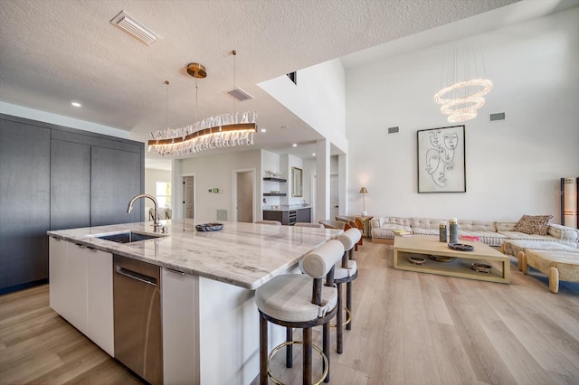 kitchen with a center island with sink, hanging light fixtures, and sink