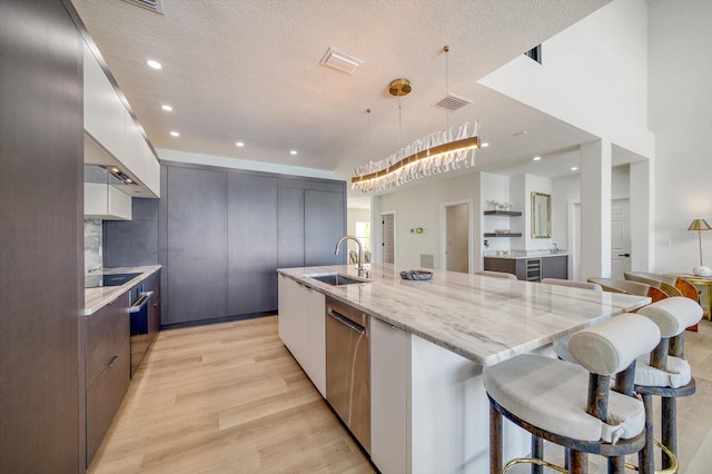 kitchen featuring pendant lighting, sink, a breakfast bar, a center island with sink, and light wood-type flooring