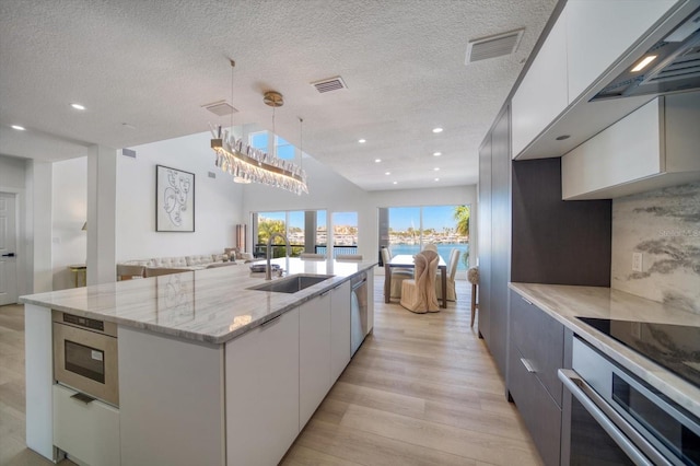 kitchen featuring appliances with stainless steel finishes, sink, an island with sink, light wood-type flooring, and white cabinets