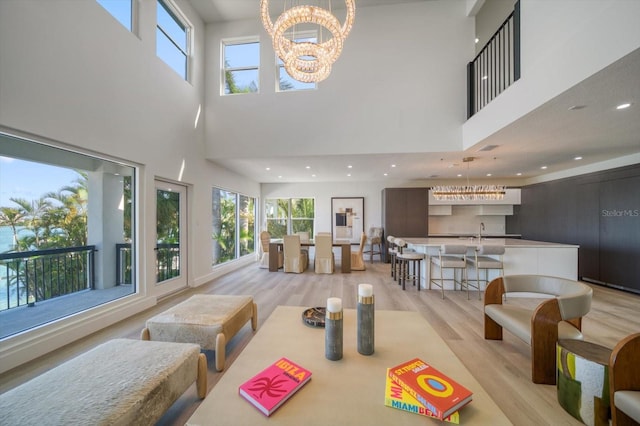 dining space featuring a chandelier, a high ceiling, light wood-type flooring, and sink