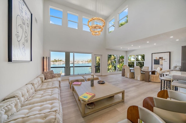 living room featuring an inviting chandelier, light hardwood / wood-style floors, a healthy amount of sunlight, and a water view