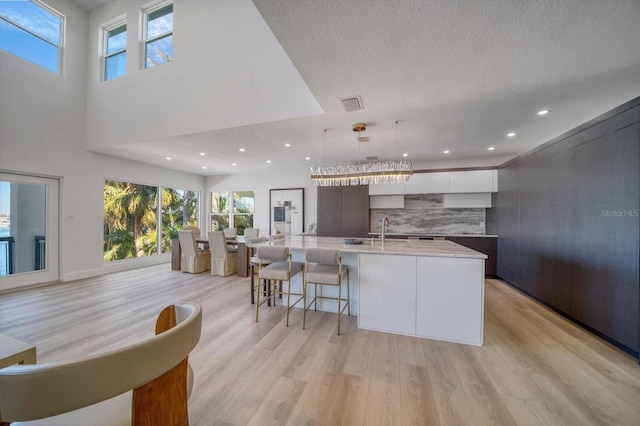 kitchen with white cabinets, a center island with sink, and light hardwood / wood-style floors