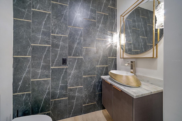 bathroom featuring tile walls, hardwood / wood-style floors, toilet, and vanity